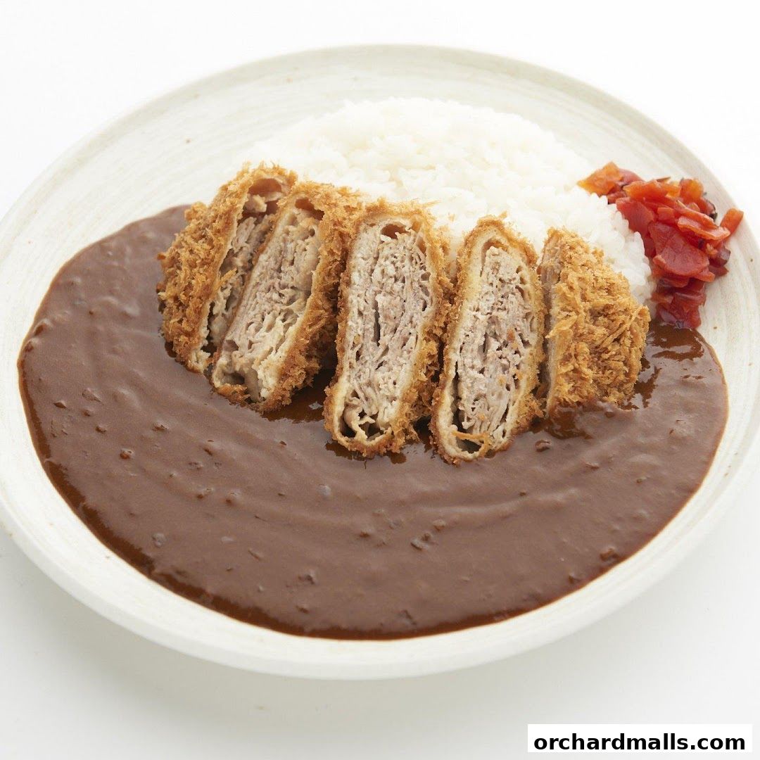 A plate of Japanese curry with sliced katsu and rice, garnished with pickles.