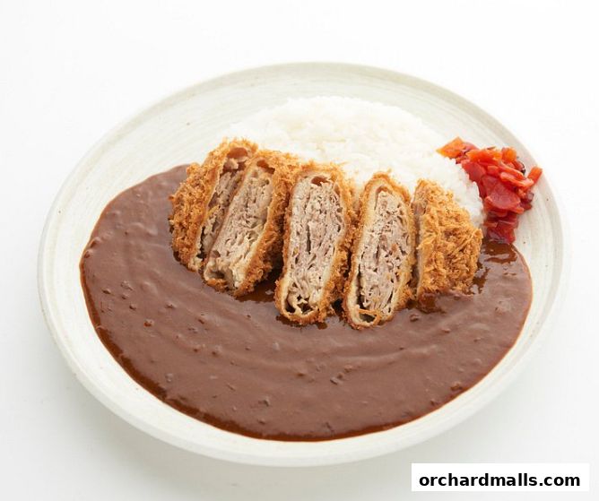 A plate of Japanese curry with sliced katsu and rice, garnished with pickled ginger.