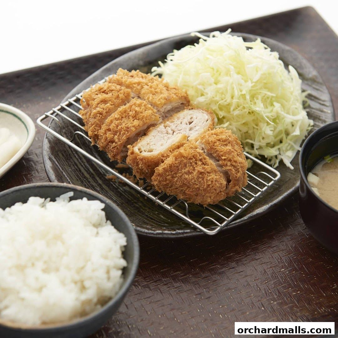 A delicious meal featuring crispy pork cutlet, shredded cabbage, rice, and miso soup.