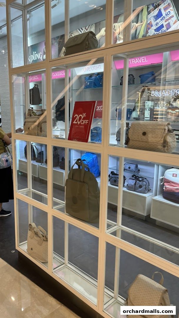 A display of Kipling bags in a store, featuring a 20% off sale sign.