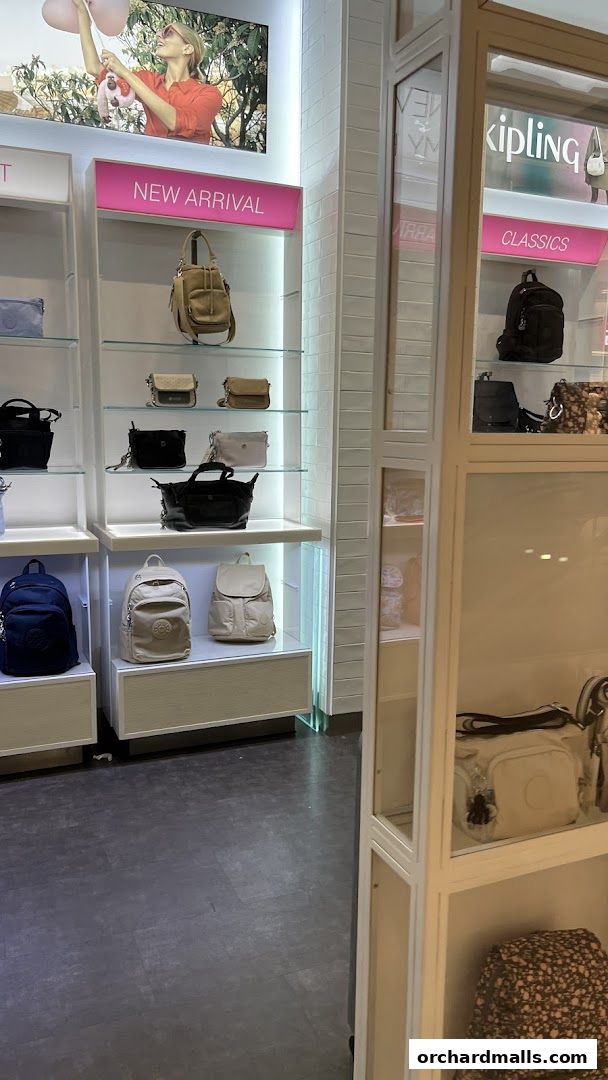 Interior view of a Kipling store showcasing new arrival and classic bags on display shelves.
