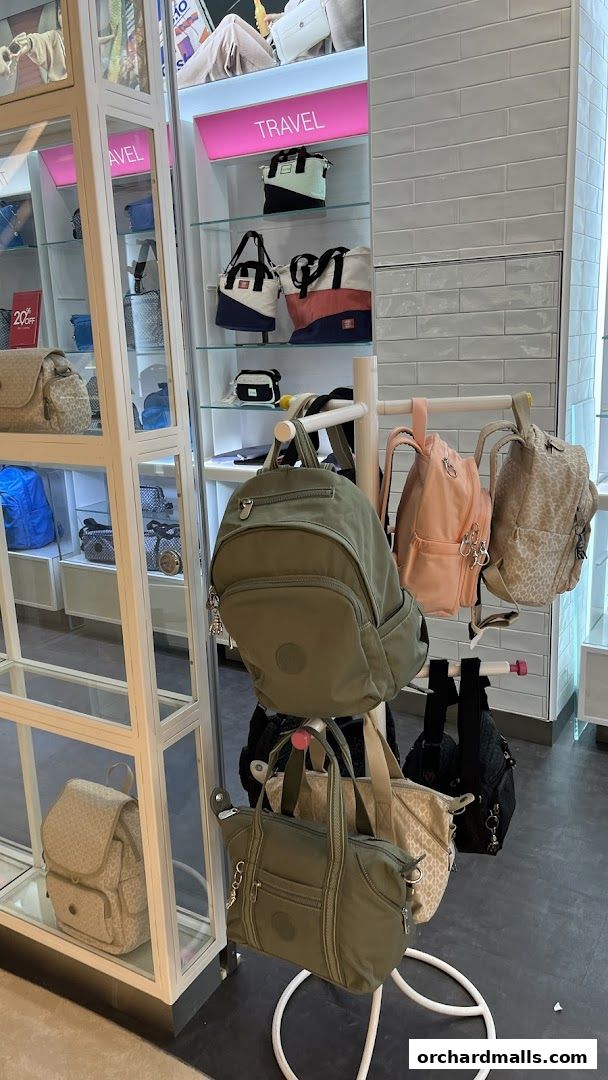 A display of various Kipling bags, including backpacks and totes, in different colors and patterns.