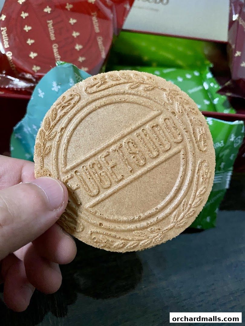A hand holds a round cookie with the name FUGETSUDO embossed on it.