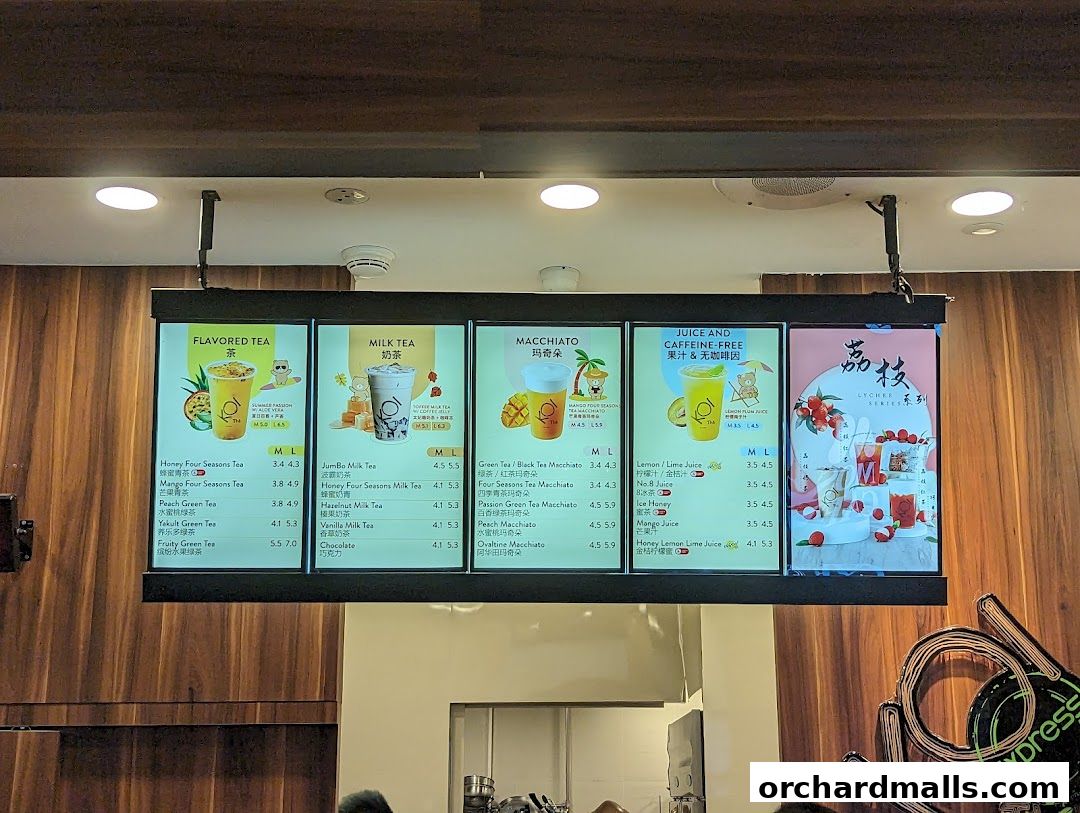 A digital menu board displaying various flavored teas, milk teas, macchiatos, and juices.