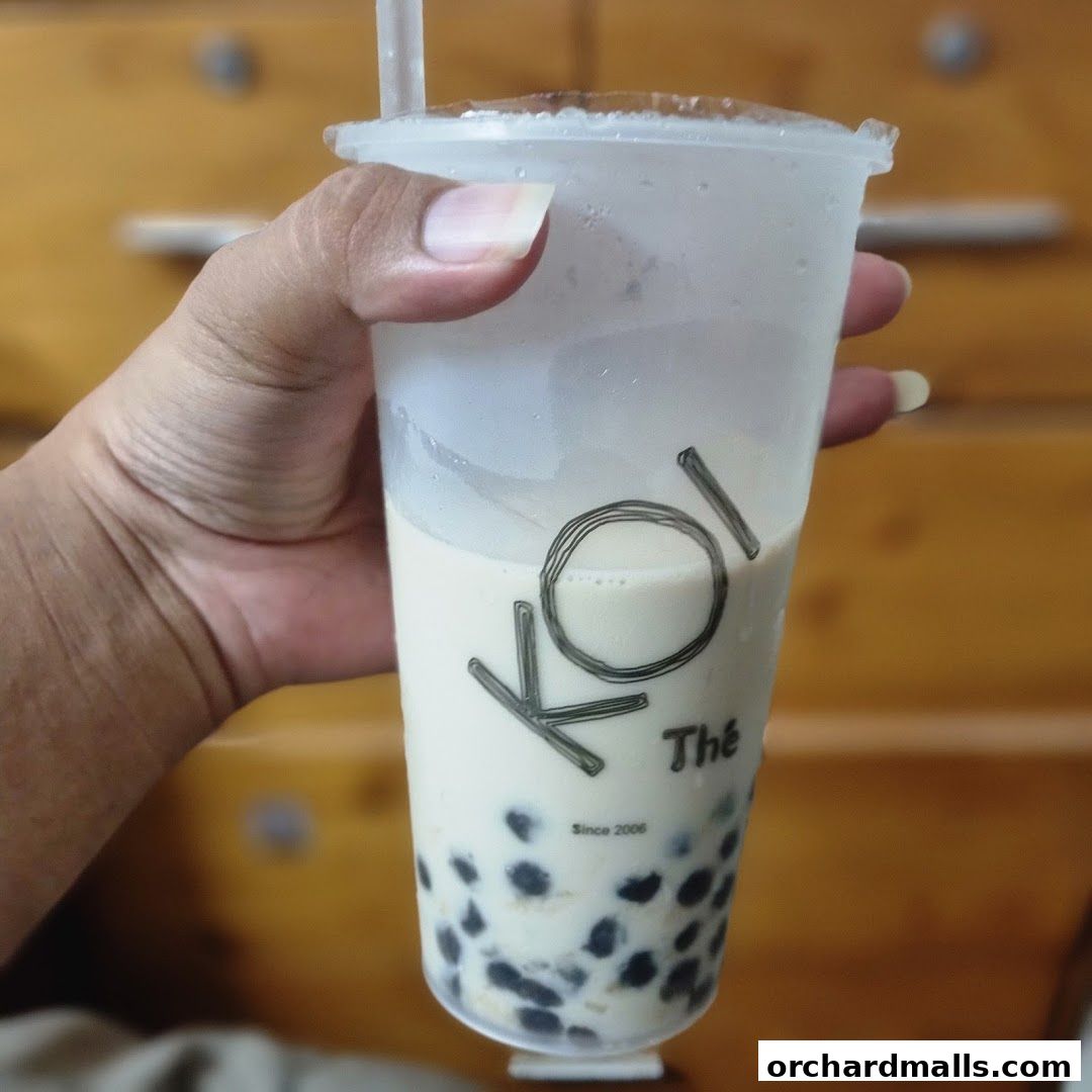 A hand holds a KOI Thé bubble tea with tapioca pearls.
