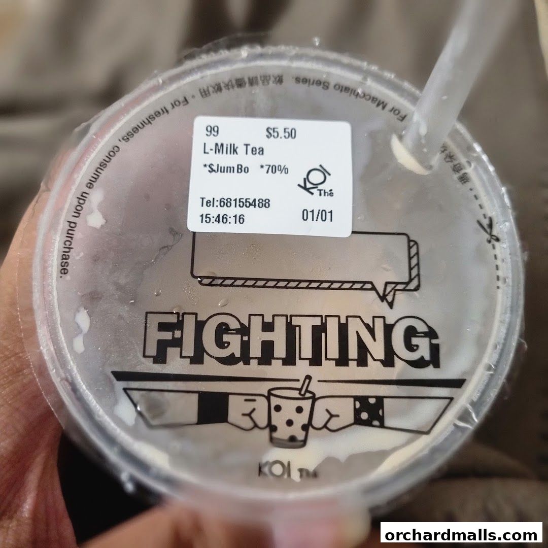 A close-up of a KOI Thé L-Milk Tea cup with a sticker showing order details.