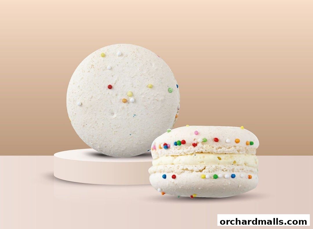 Two white macarons with colorful sprinkles on a light brown background.