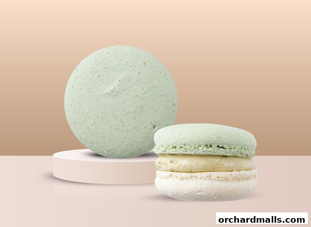 Two pastel green macarons, one whole and one stacked, on a display stand.