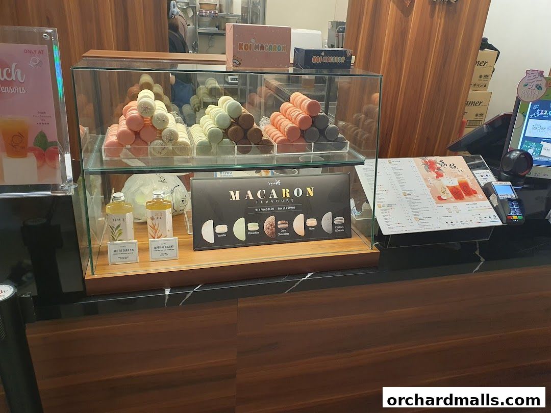 KOI Thé Express Takashimaya display case with macarons, bottled drinks, and a menu.