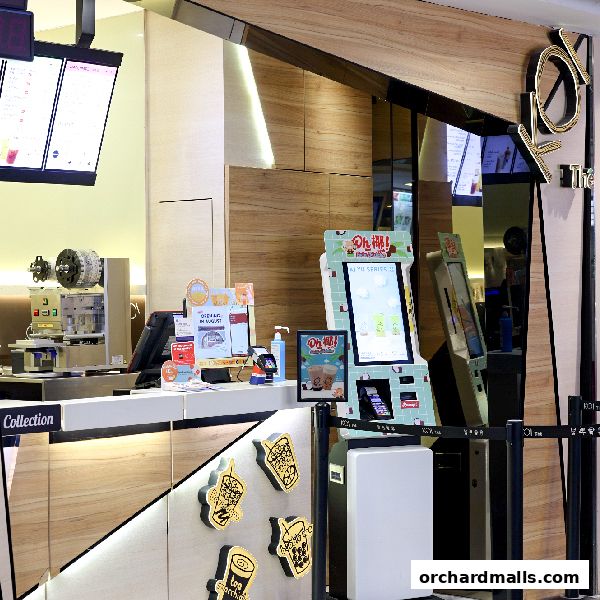 The interior of a KOI Thé shop with a counter, ordering kiosks, and branding.