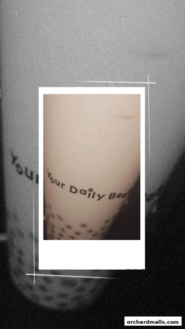 A close-up of a KOI Thé cup with the slogan 'Your Daily Brew' and tapioca pearls.