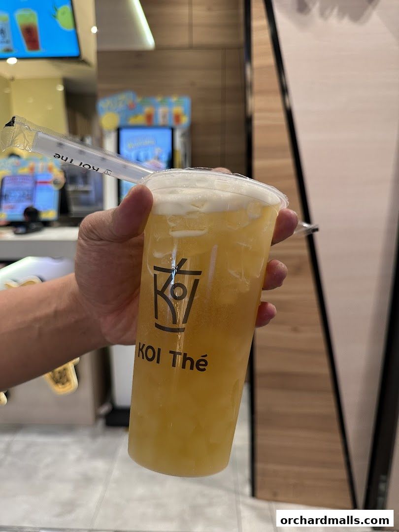 A hand holds a refreshing KOI Thé bubble tea with a creamy foam topping.