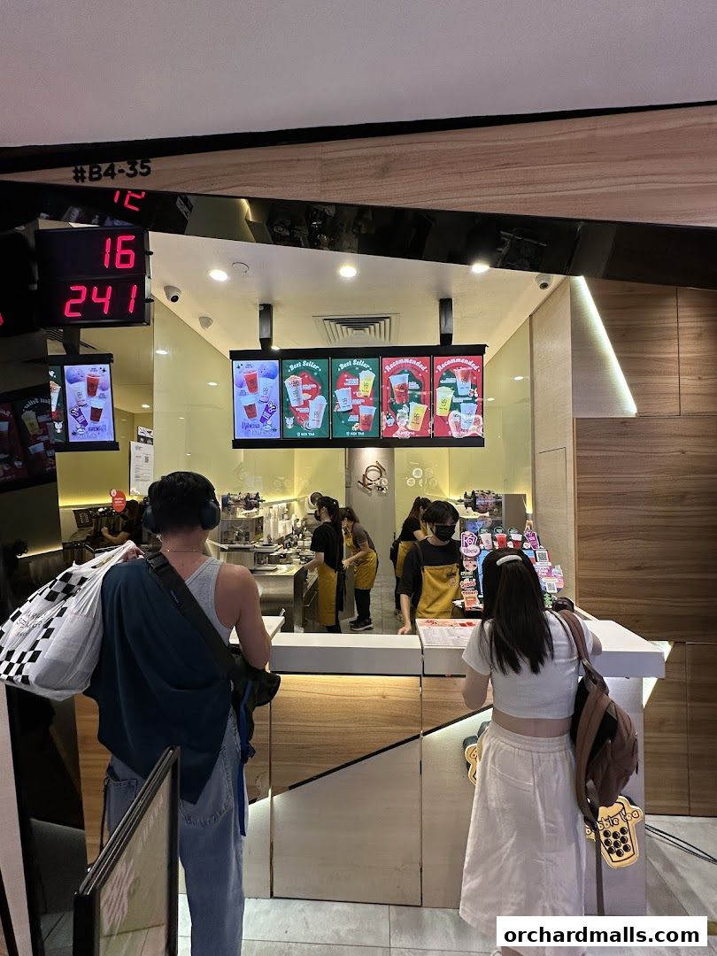 Customers ordering drinks at a busy KOI Thé counter with staff preparing beverages.