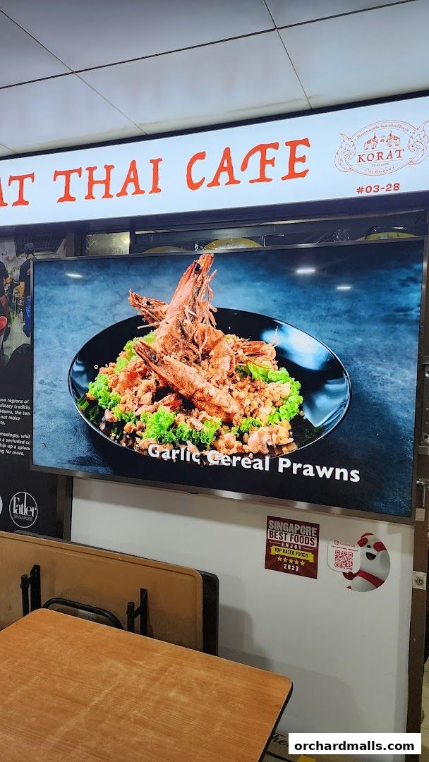 A digital display shows a close-up of Garlic Cereal Prawns at Korat Thai Cafe.
