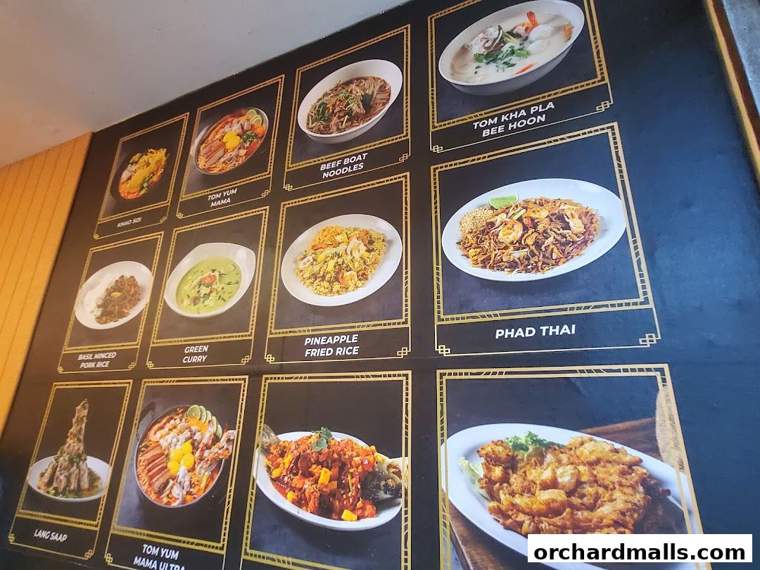 A wall display showcasing various Thai dishes with appetizing images and names.