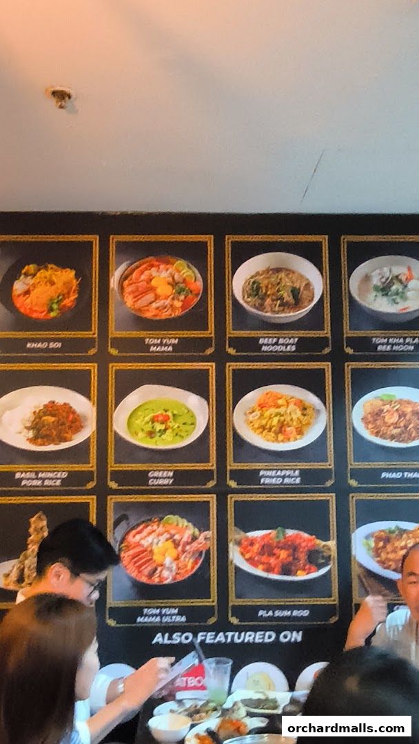 A wall display showcasing various Thai dishes with their names and images.