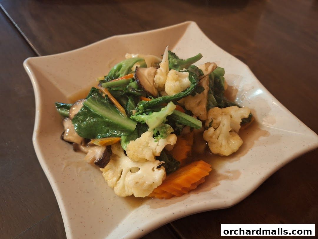 A plate of stir-fried mixed vegetables with cauliflower, broccoli, carrots, and mushrooms.
