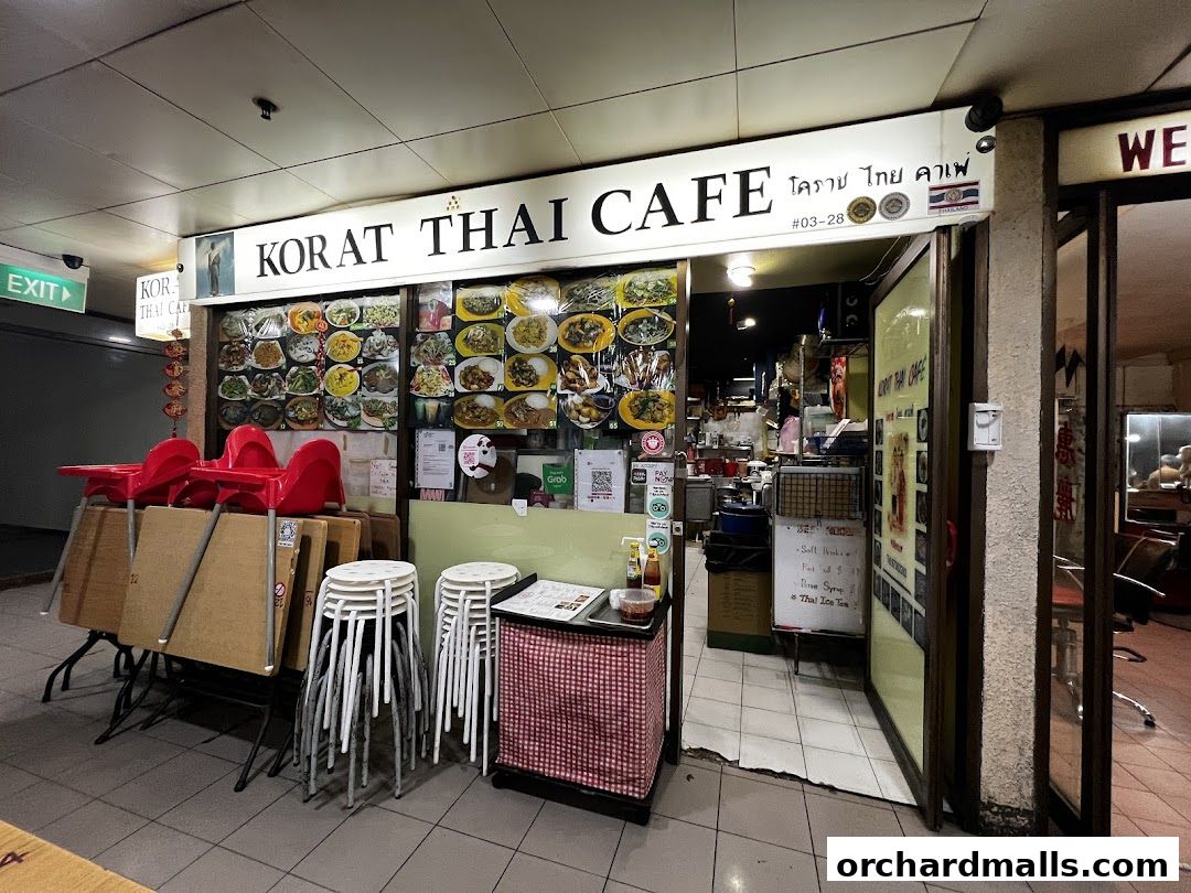 Exterior of Korat Thai Cafe with food displays, seating, and entrance visible.