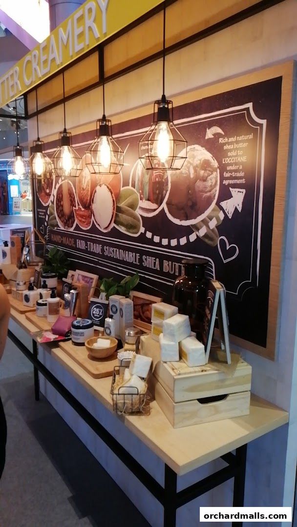 A display of L'Occitane shea butter products with a chalkboard highlighting their benefits.