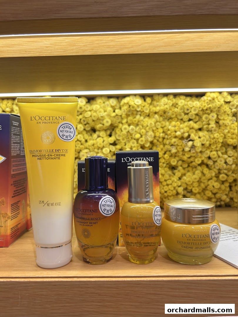 L'Occitane Immortelle Divine skincare products displayed on a wooden shelf.