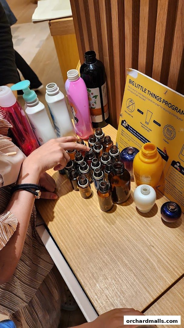 A display of various empty beauty product bottles and small amber vials on a wooden counter.