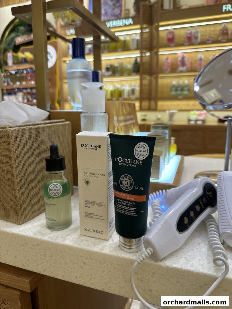 L'Occitane products including anti-hair loss serum and anti-frizz serum displayed on a counter.