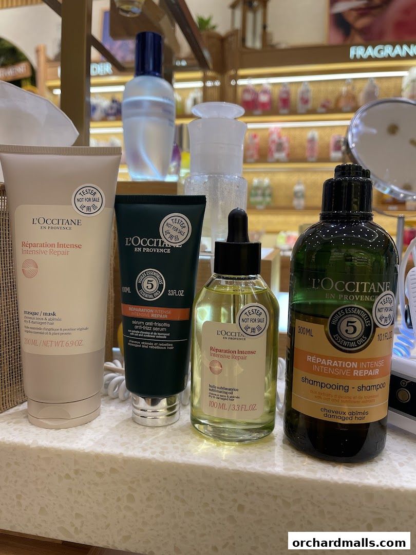 A display of L'Occitane Intensive Repair hair care products, including a mask, serum, and shampoo.