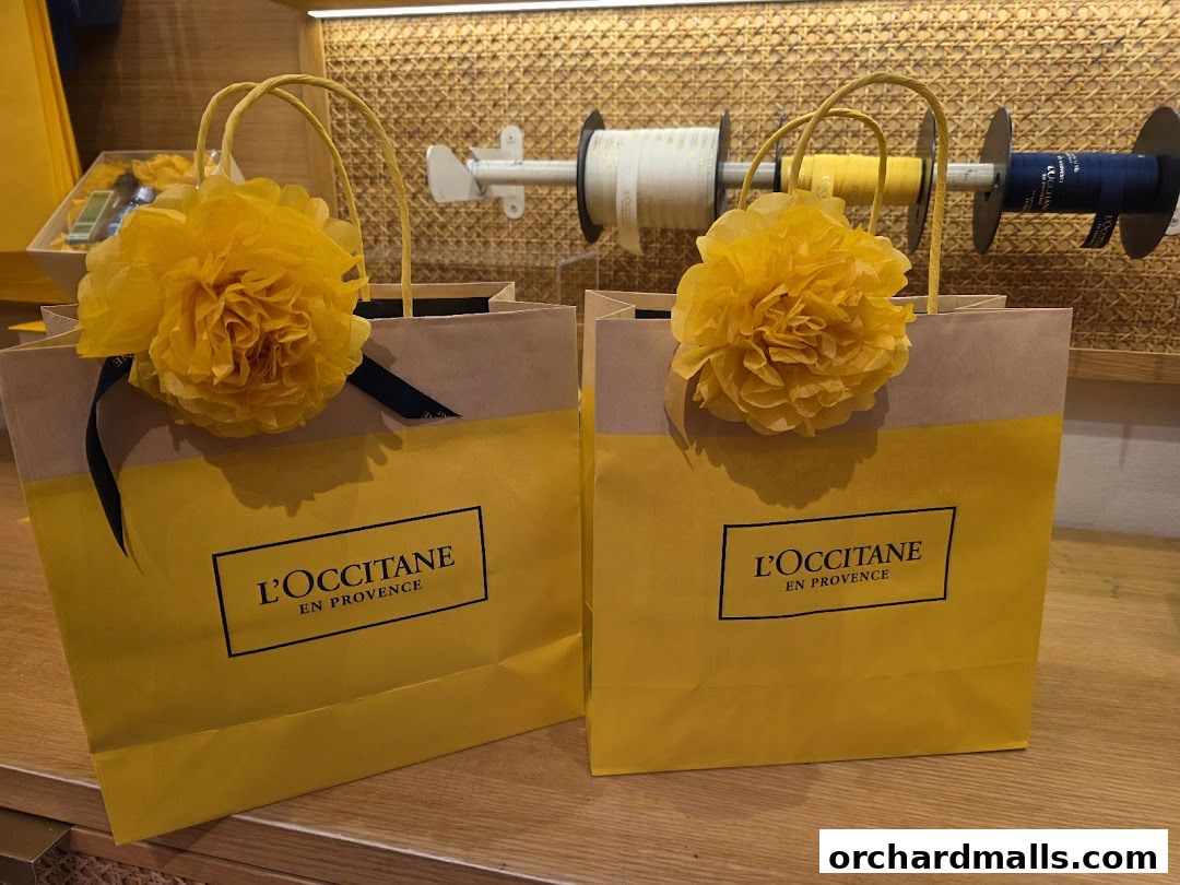 Two yellow shopping bags from L'Occitane decorated with large yellow tissue paper flowers.