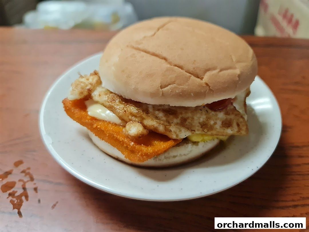 A close-up of a delicious burger with fried egg and crispy patty on a white plate.