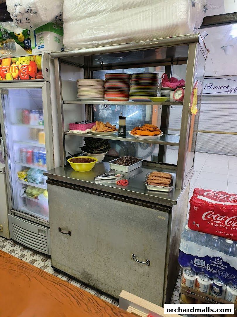 A snack bar display with food items, drinks, and stacked plates.