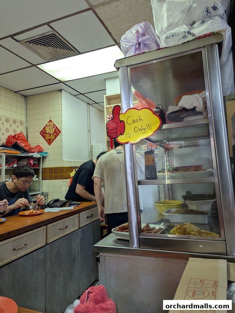 Interior of a snack bar with customers and food display, showing a 'Cash Only' sign.