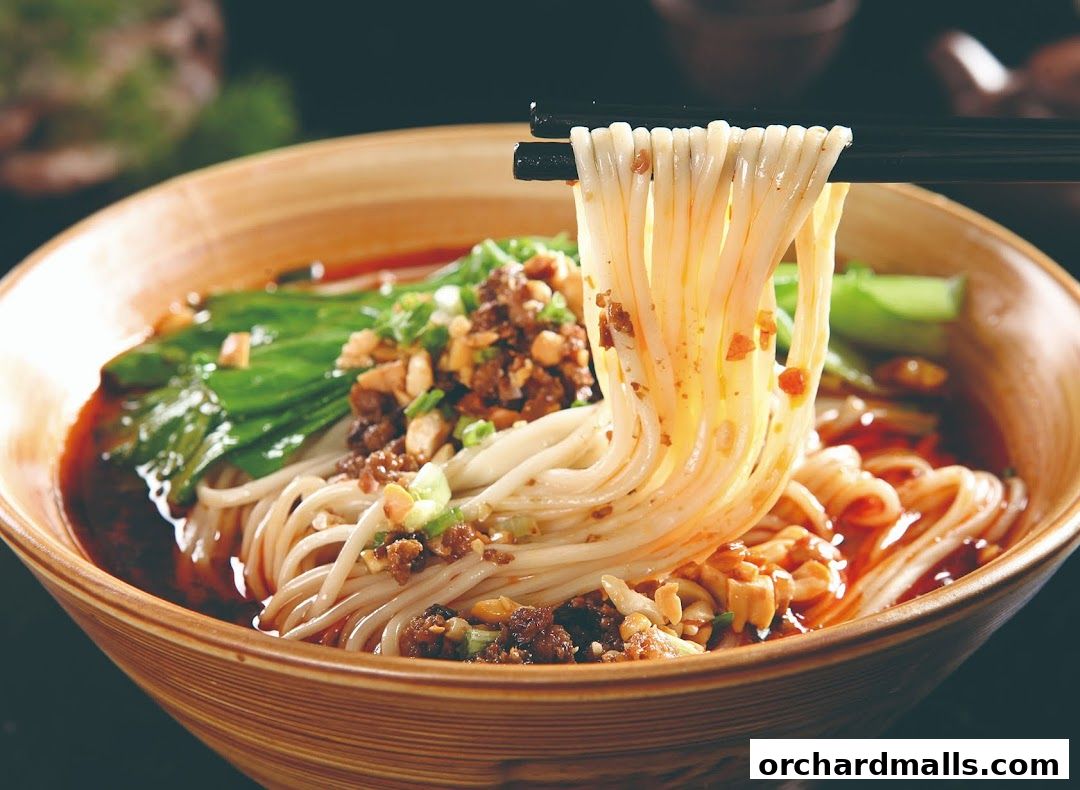 A close-up shot of a steaming bowl of noodles with minced meat and greens.
