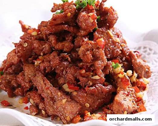 A close-up shot of a pile of crispy, spicy fried beef with chili and scallions.
