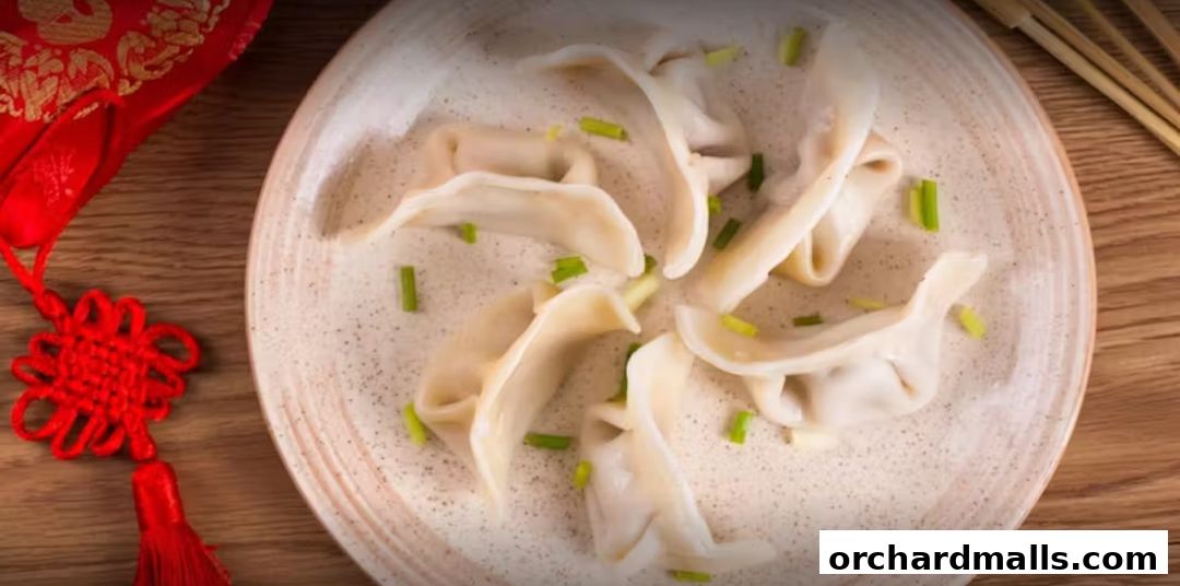 A plate of delicious dumplings garnished with chopped green onions, with red Chinese knot decor.