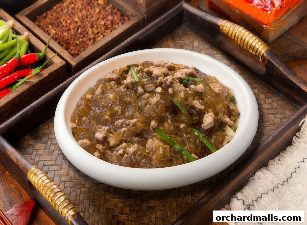 A close-up of a savory noodle dish with minced meat and green onions.