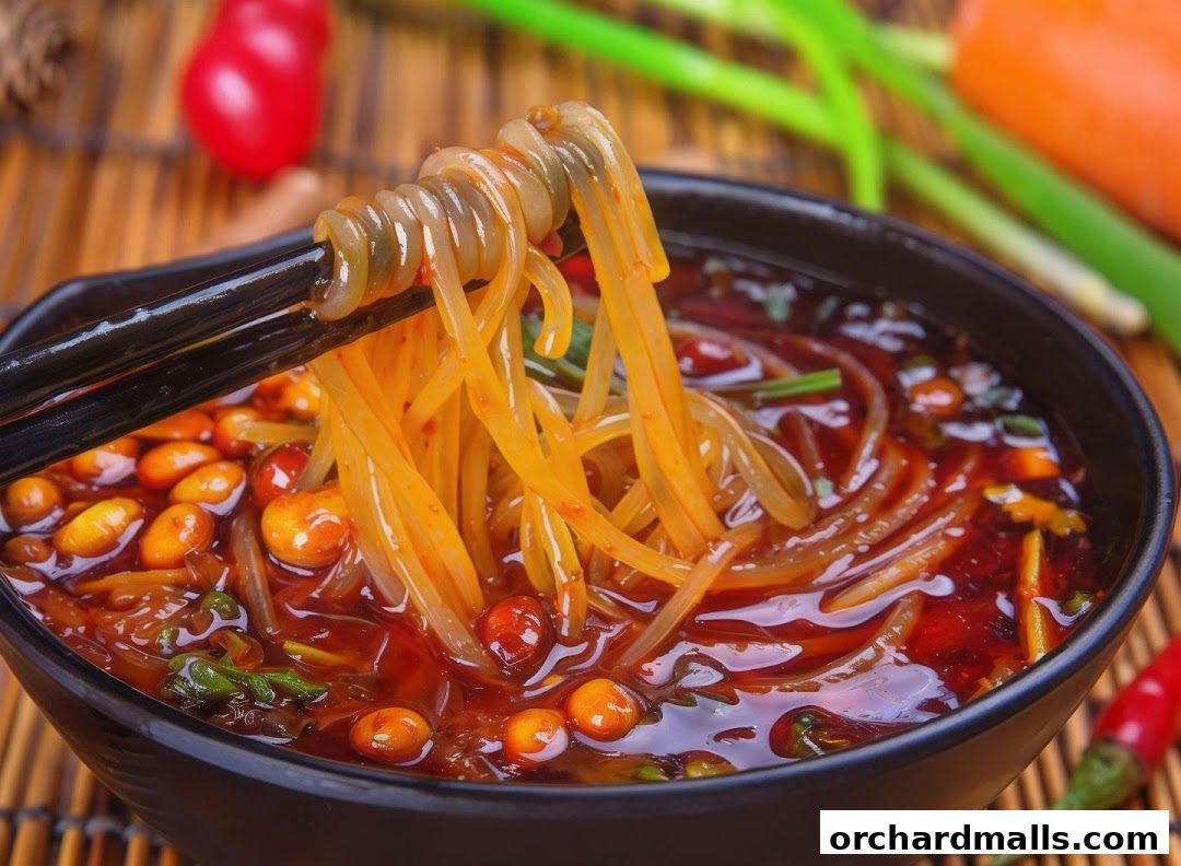 A close-up of spicy noodles with peanuts and chili oil in a black bowl.