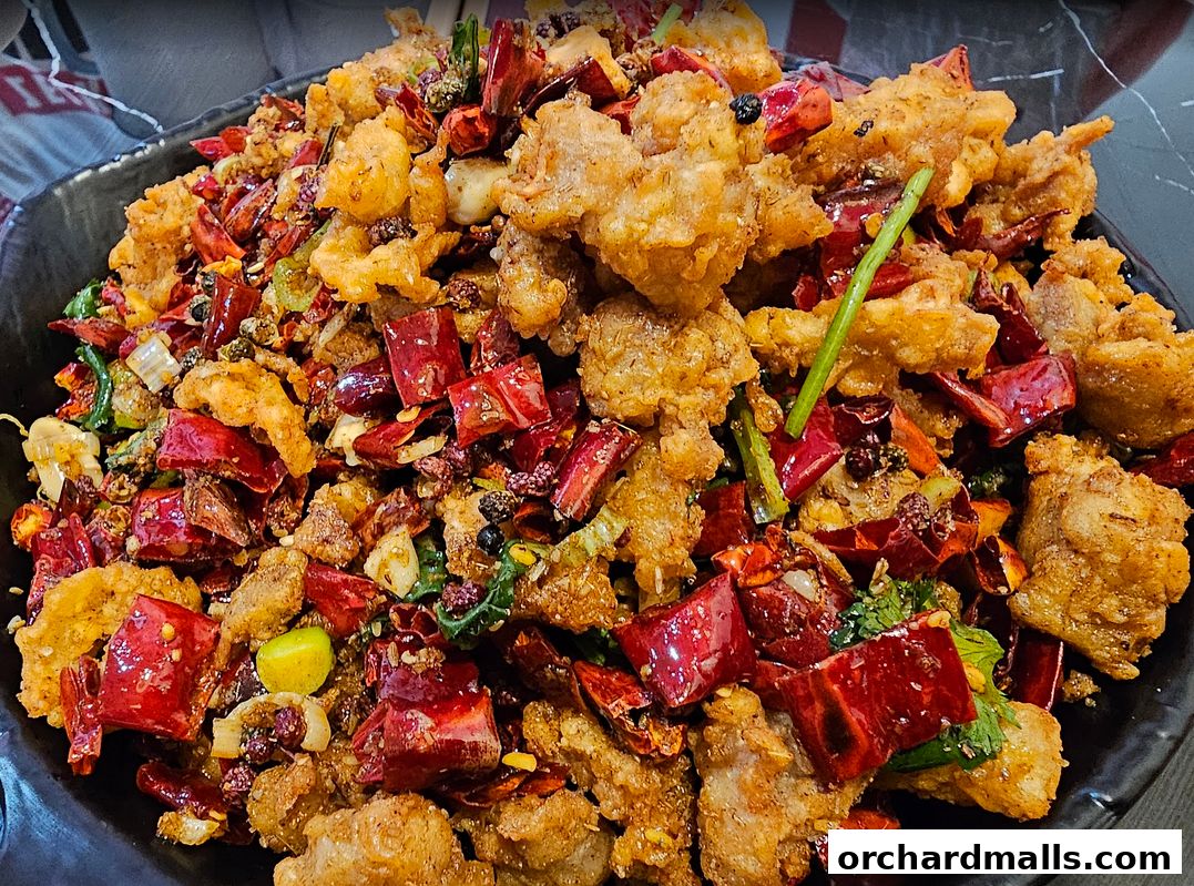 A close-up shot of a spicy Sichuan dish with fried chicken, dried chilies, and Sichuan peppercorns.