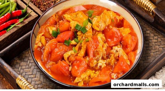 A close-up of a delicious tomato and egg stir-fry dish, garnished with green onions.