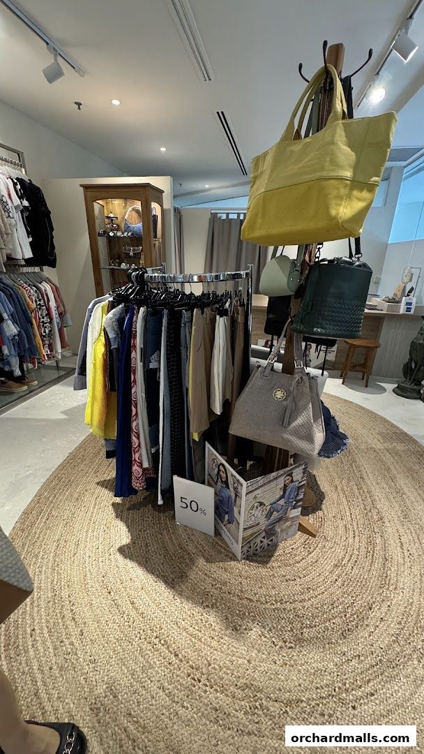 Interior view of a clothing boutique with racks of apparel and handbags on display.