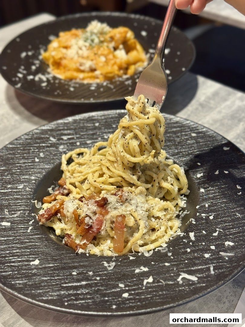 A fork twirls spaghetti carbonara with bacon and parmesan cheese.