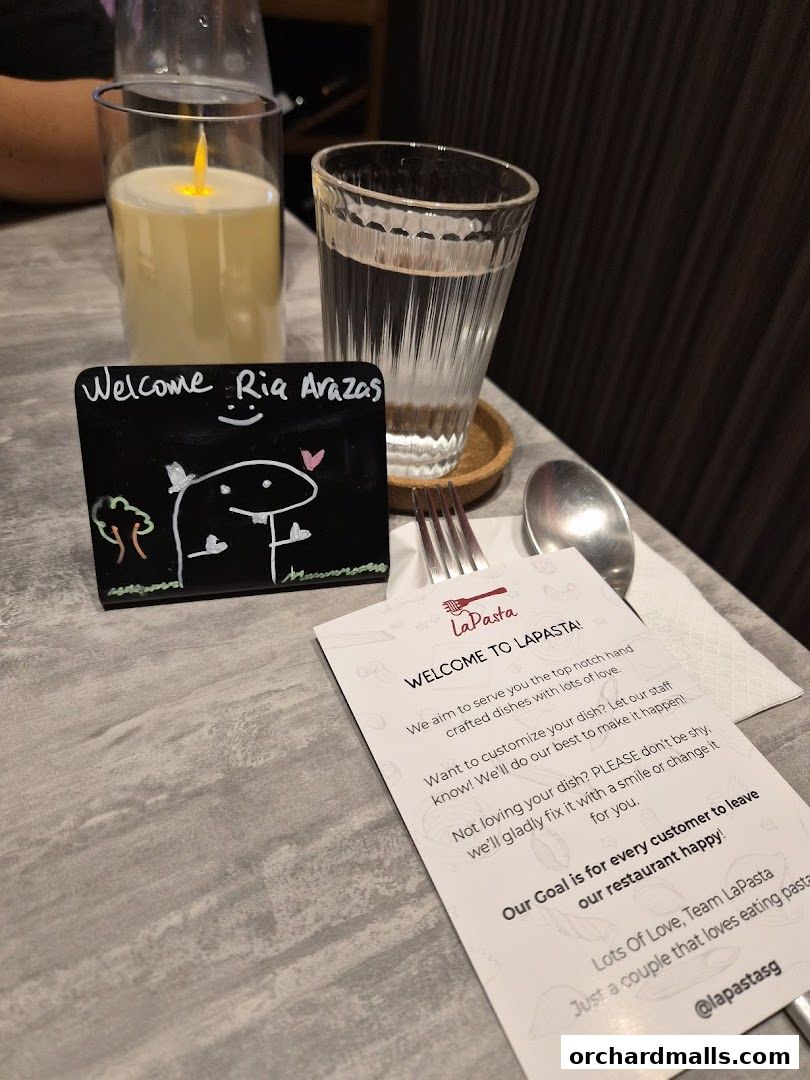 A table setting at LaPasta with a welcome sign, drinks, and a menu card.