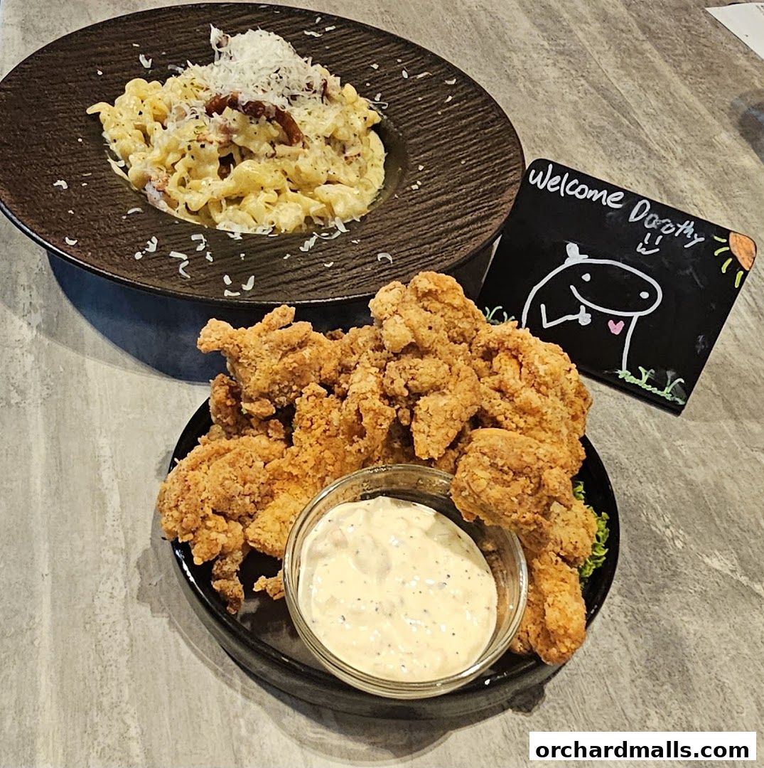 A plate of crispy fried chicken and a bowl of pasta are displayed with a welcome sign.