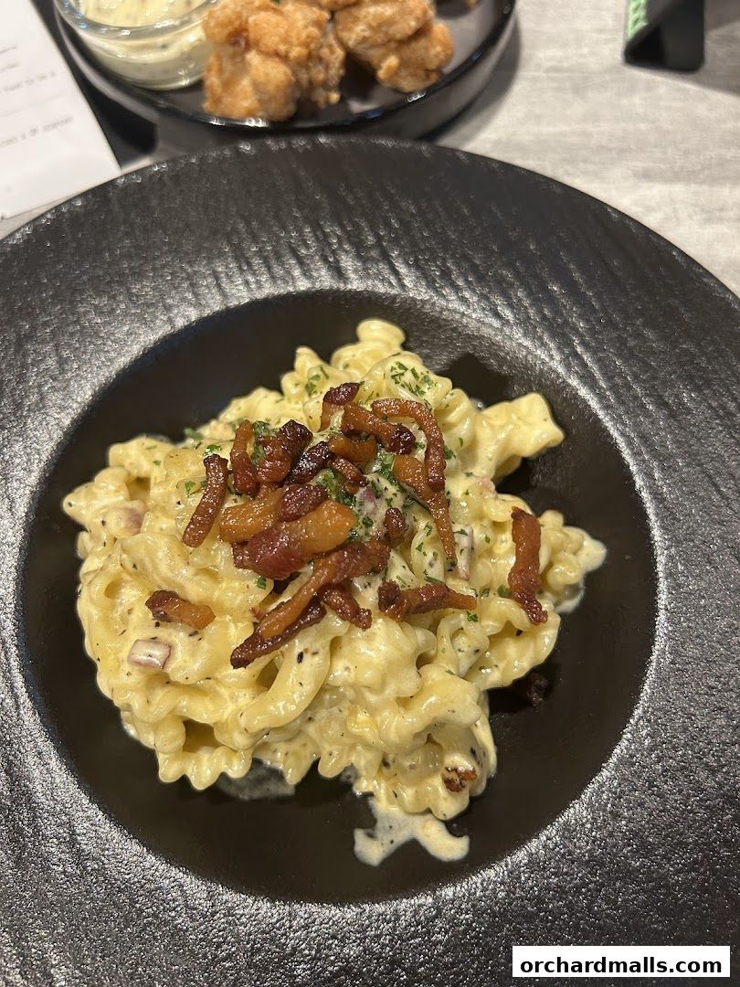 A close-up shot of a creamy pasta dish topped with crispy bacon.