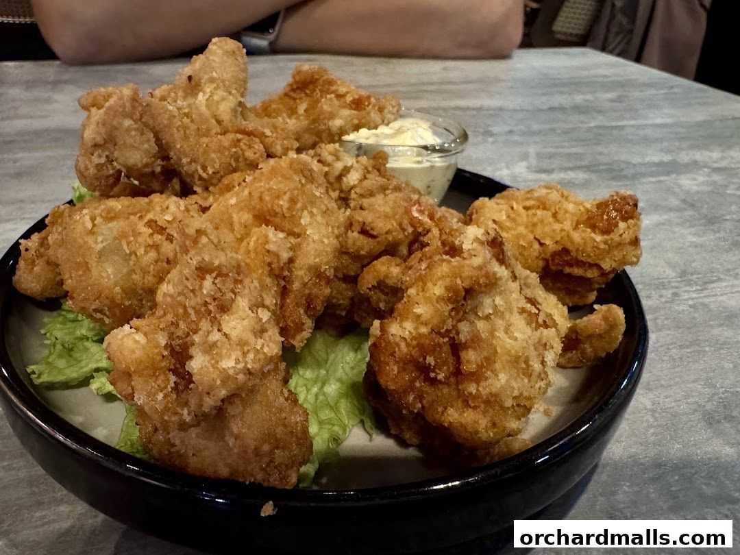 A close-up shot of a plate of crispy fried chicken pieces with a side of dipping sauce.