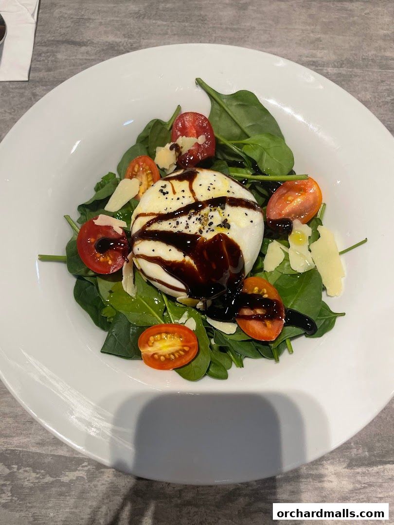 A fresh burrata salad with cherry tomatoes, spinach, and balsamic glaze.