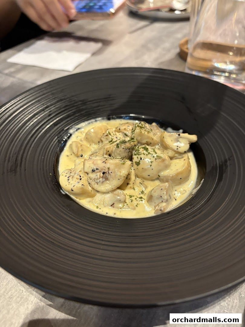 A close-up of a creamy mushroom pasta dish served in a black bowl.