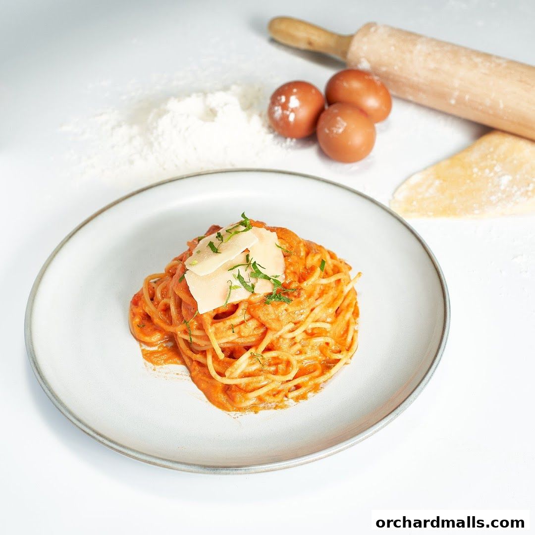 A plate of spaghetti with creamy tomato sauce, garnished with cheese and herbs.
