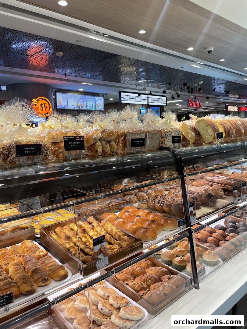 A display case filled with a variety of freshly baked breads, pastries, and buns at Lavender Bakery.