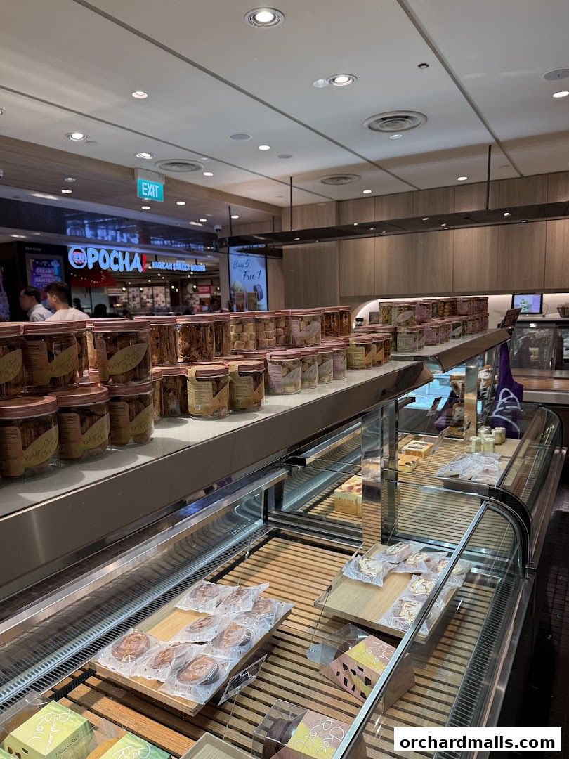 Interior view of Lavender Bakery showcasing rows of packaged baked goods and cakes in display cases.