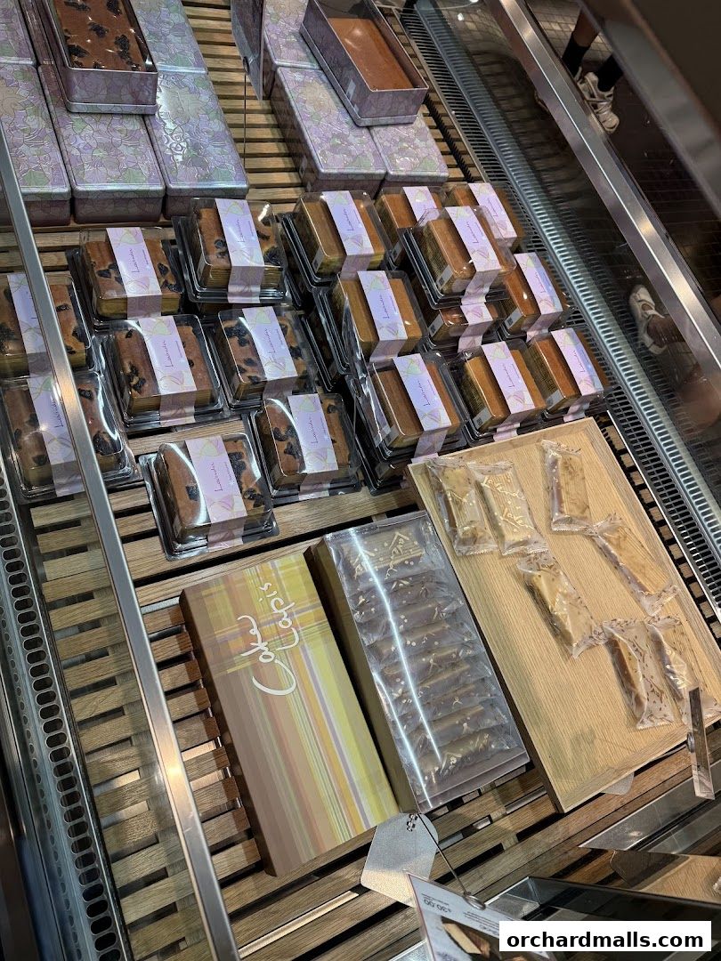 A display of assorted cakes and pastries in clear packaging and decorative boxes.